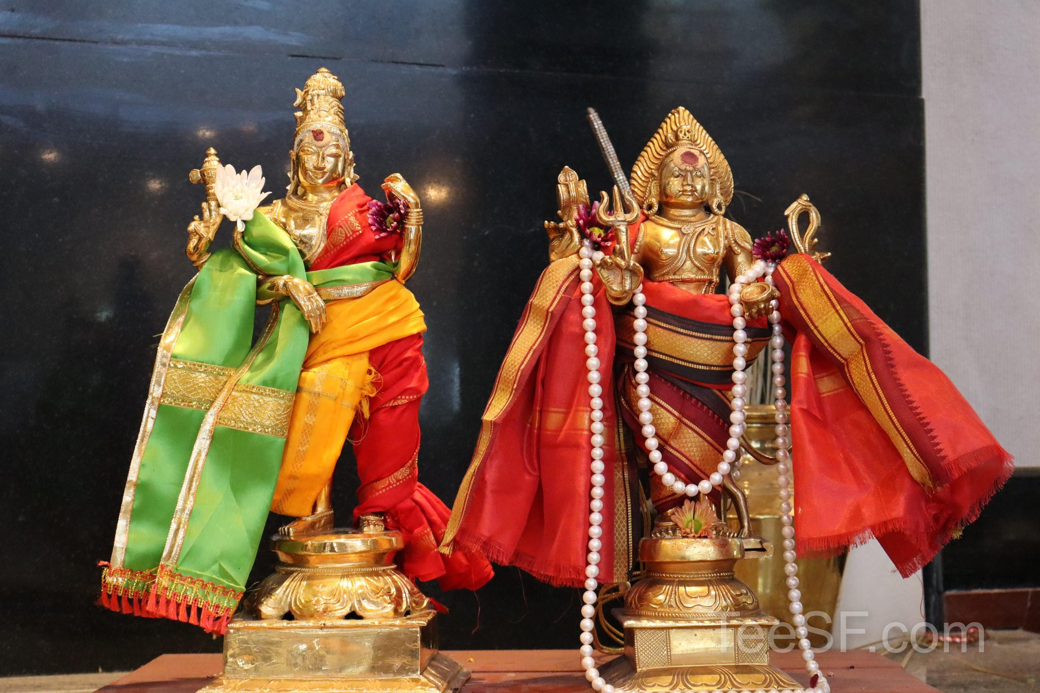Two colorful shrine figures in red and green with gold details.